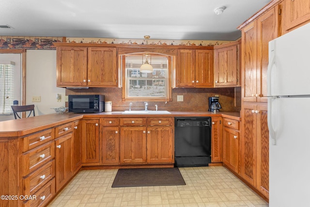 kitchen featuring a sink, black appliances, a peninsula, and a healthy amount of sunlight