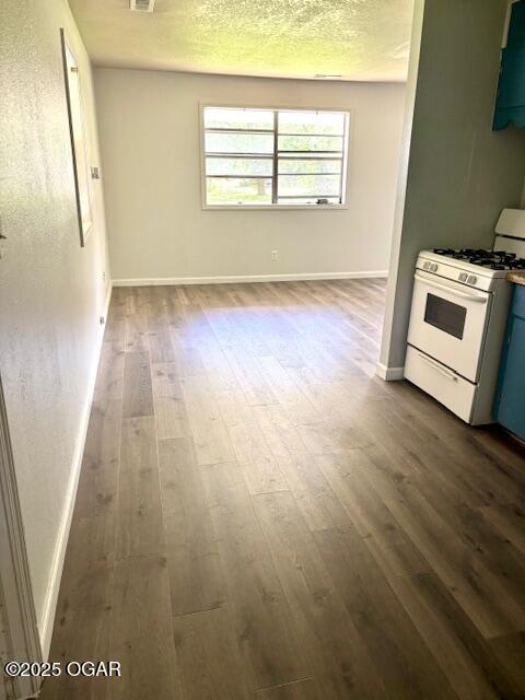 1530 S Oronogo St, Webb City, MO 64870 - kitchen featuring white range with gas stovetop, dark wood-style floors, baseboards, and blue cabinetry