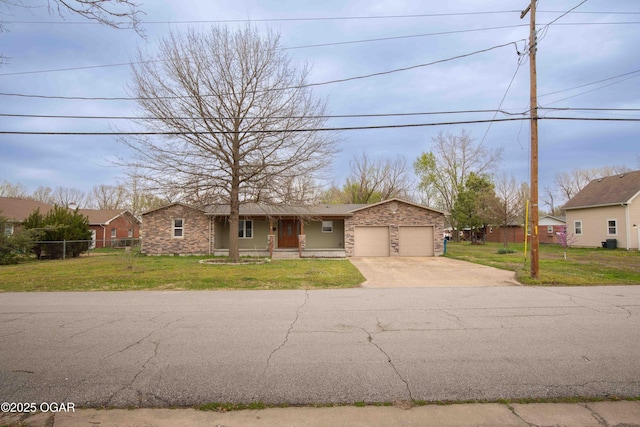 view of front of home featuring driveway, a garage, a front lawn, and stone siding