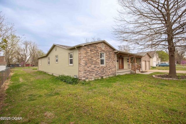 view of property exterior featuring stone siding, fence, an attached garage, concrete driveway, and a yard