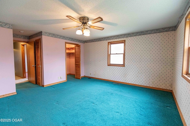 unfurnished bedroom with baseboards, wallpapered walls, carpet floors, and a textured ceiling
