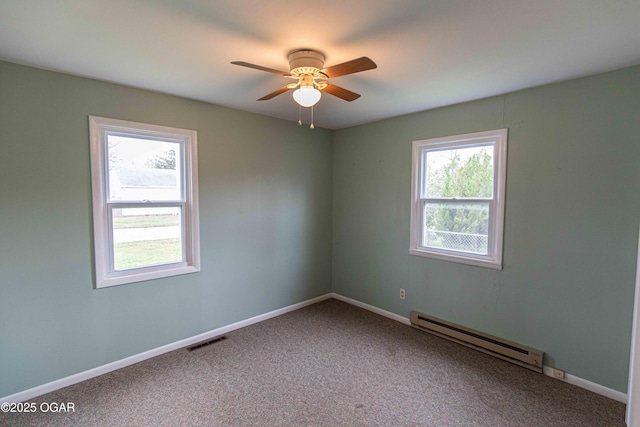 spare room with a baseboard heating unit, carpet flooring, baseboards, ceiling fan, and visible vents