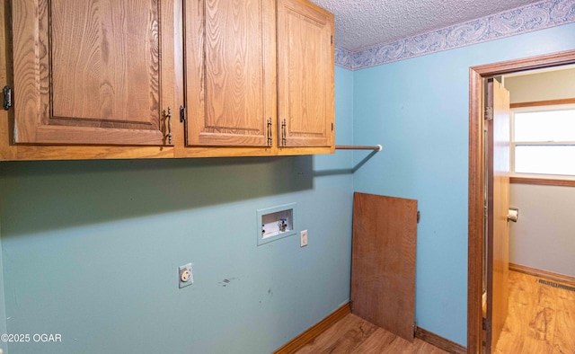 washroom with a textured ceiling, visible vents, hookup for a washing machine, wood finished floors, and cabinet space