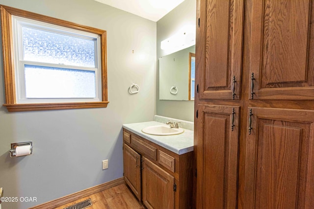 bathroom with baseboards, visible vents, vanity, and wood finished floors