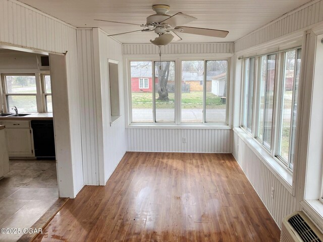 323 W Maple St, Columbus, KS 66725 - unfurnished sunroom featuring a sink, a wealth of natural light, wood finished floors, and an AC wall unit