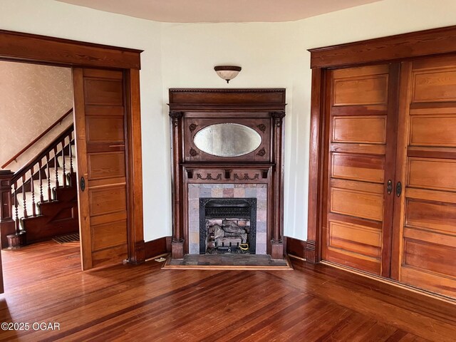 323 W Maple St, Columbus, KS 66725 - unfurnished living room featuring baseboards, a tile fireplace, stairway, and wood finished floors