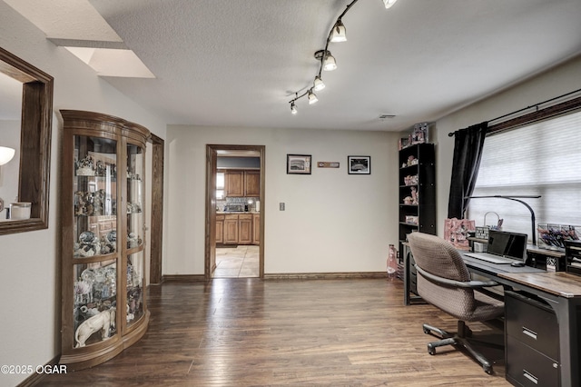 office space featuring baseboards, light wood-style floors, and a textured ceiling