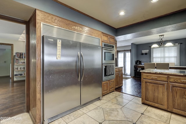 kitchen with light countertops, recessed lighting, light tile patterned floors, stainless steel appliances, and brown cabinetry