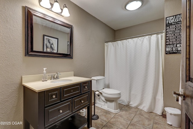 full bath featuring tile patterned floors, a shower with shower curtain, toilet, vanity, and a textured wall
