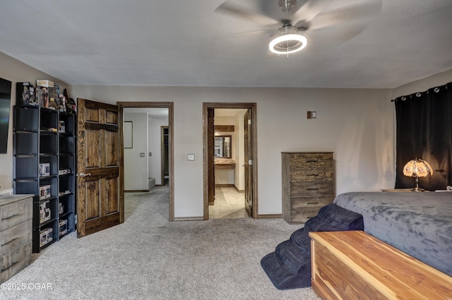 carpeted bedroom with ensuite bathroom, baseboards, and ceiling fan