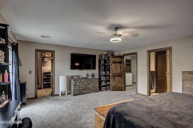 carpeted bedroom featuring baseboards, visible vents, a walk in closet, and a ceiling fan