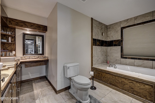 bathroom featuring toilet, vanity, baseboards, and a bath