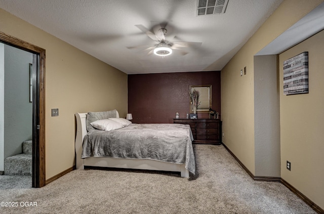 bedroom featuring baseboards, a textured ceiling, visible vents, and light colored carpet