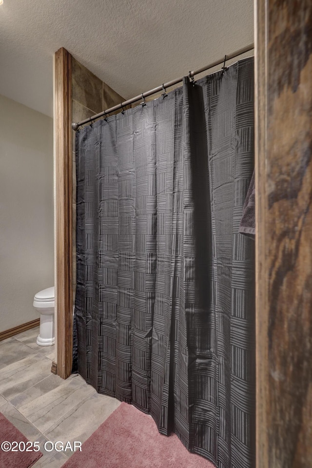 full bathroom featuring a shower with curtain, toilet, and a textured ceiling