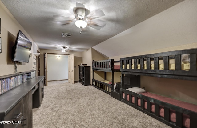 bedroom with a textured ceiling, light colored carpet, and visible vents