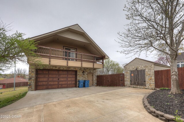view of property exterior featuring a balcony, an attached garage, stone siding, and concrete driveway