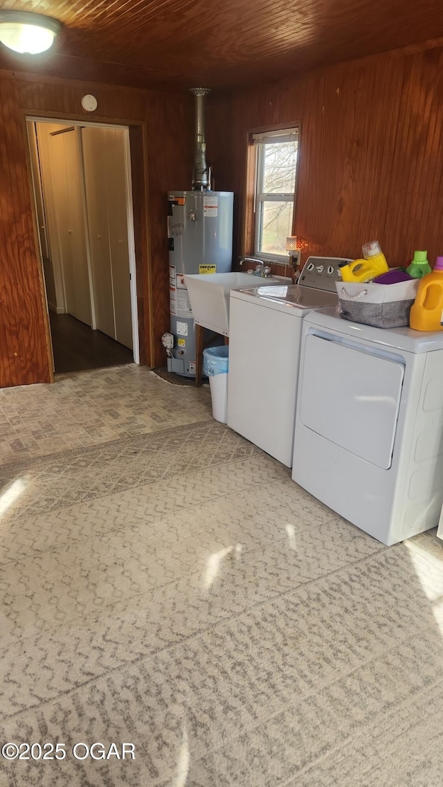 clothes washing area with laundry area, wood walls, water heater, wooden ceiling, and washing machine and dryer