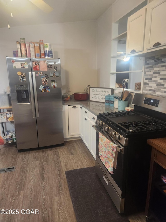 kitchen featuring appliances with stainless steel finishes, white cabinetry, decorative backsplash, wood finished floors, and visible vents