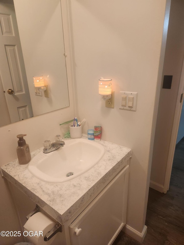 bathroom featuring baseboards, wood finished floors, and vanity