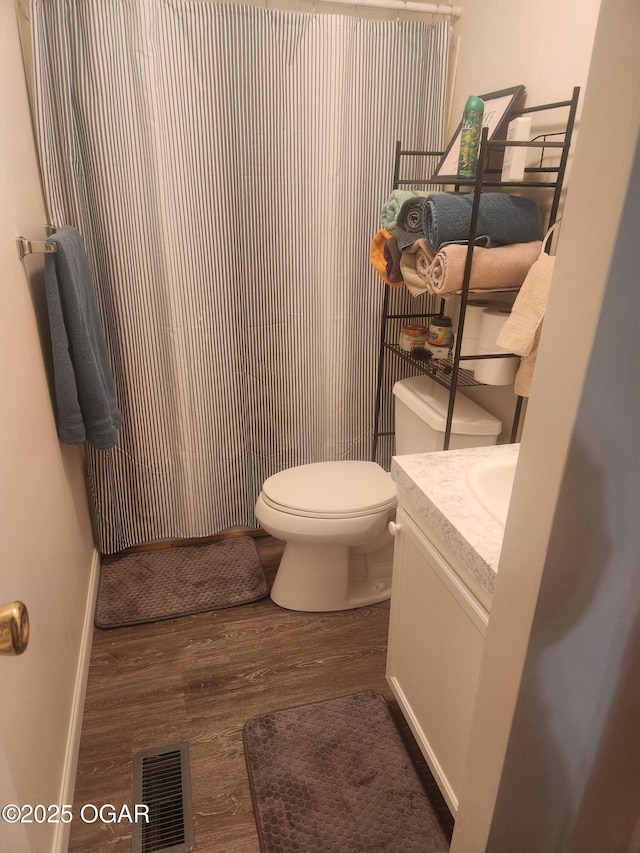bathroom with vanity, toilet, baseboards, wood finished floors, and visible vents