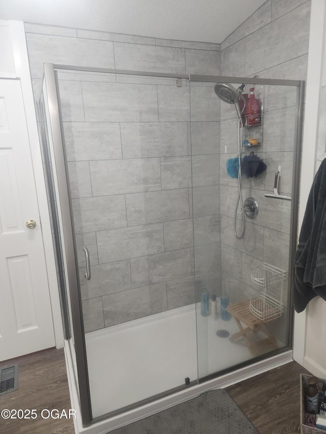 full bath featuring a shower stall, wood finished floors, and visible vents