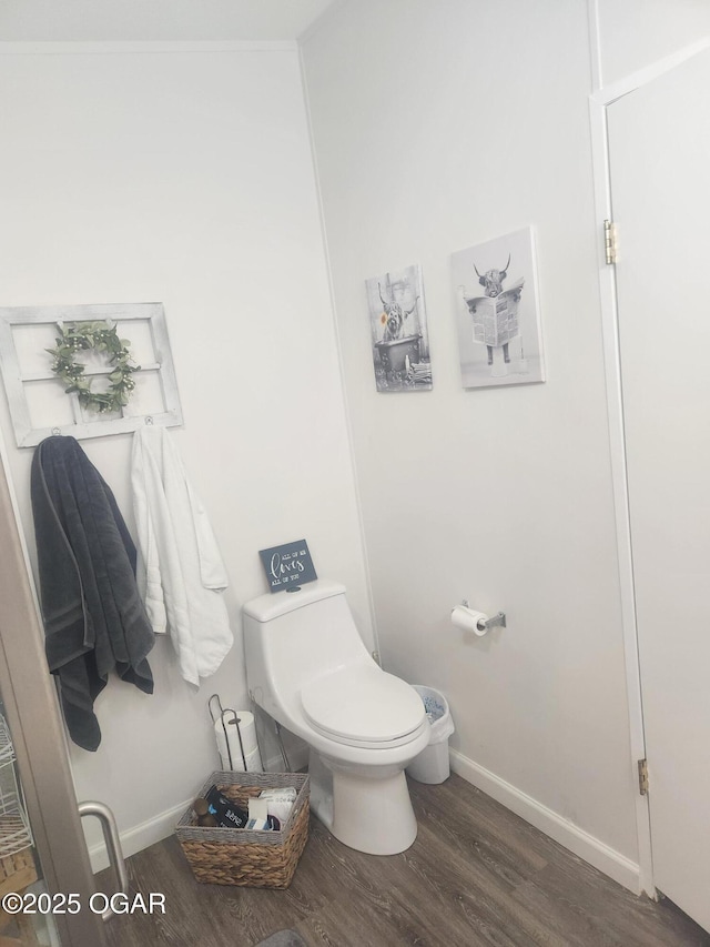 bathroom with baseboards, wood finished floors, and toilet