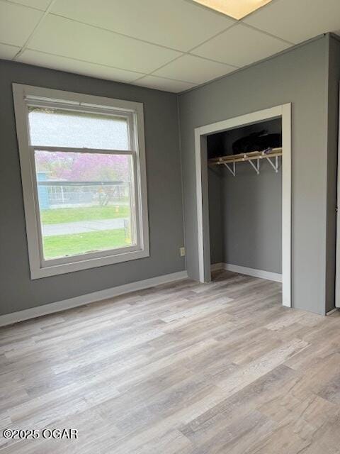 201 N Georgia St, Pittsburg, KS 66762 - unfurnished bedroom with a drop ceiling, light wood-style flooring, a closet, and baseboards