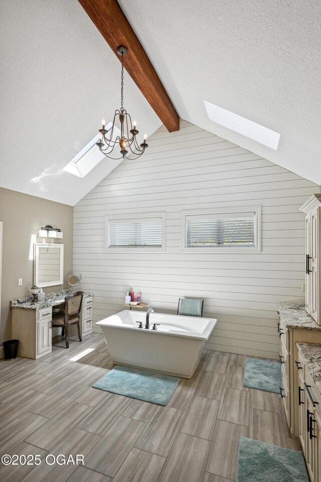 1624 Liam St, Carthage, MO 64836 - bathroom featuring vaulted ceiling with skylight, an inviting chandelier, wood finish floors, vanity, and a freestanding bath
