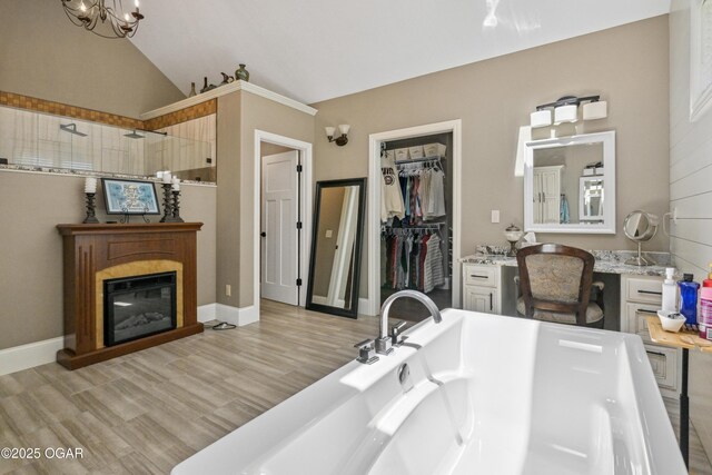 1624 Liam St, Carthage, MO 64836 - full bath featuring a glass covered fireplace, vaulted ceiling, a soaking tub, a walk in shower, and wood finished floors