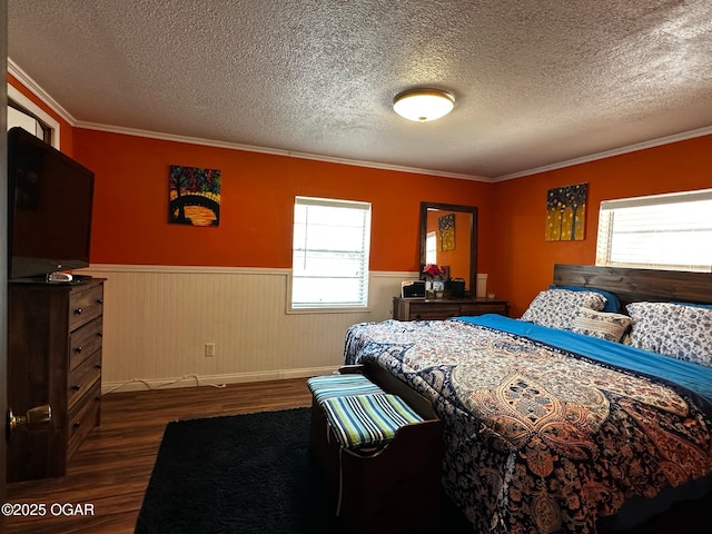 bedroom with a textured ceiling, dark wood-style flooring, multiple windows, and a wainscoted wall