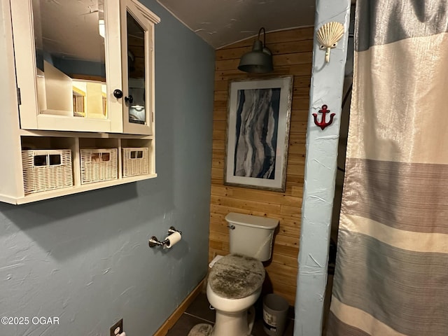 bathroom featuring wooden walls, a shower with curtain, vaulted ceiling, and toilet