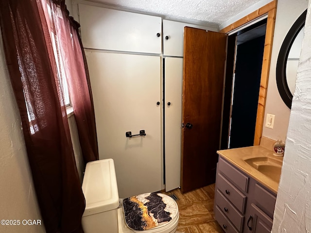 bathroom featuring toilet, a textured ceiling, and vanity