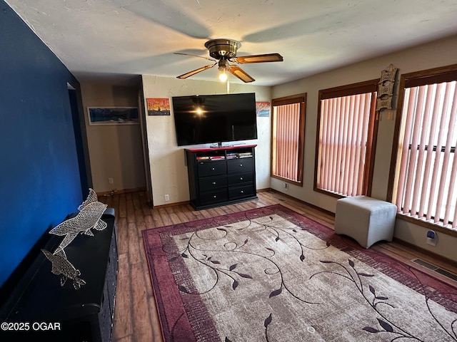 interior space with visible vents, baseboards, a ceiling fan, and wood finished floors