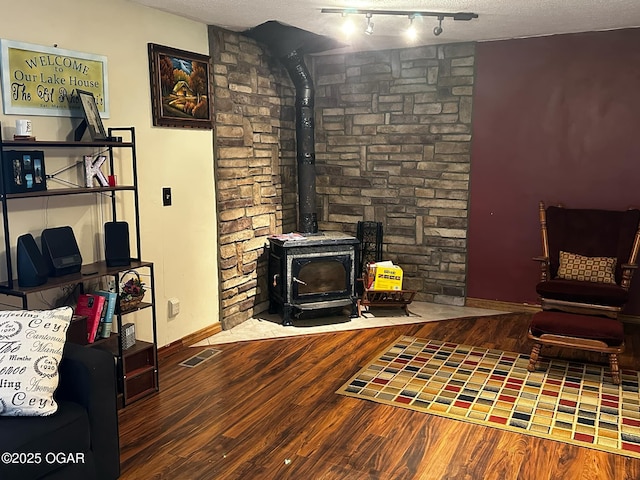 living area with visible vents, a textured ceiling, baseboards, and wood finished floors
