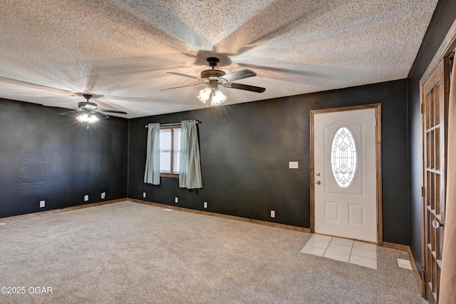carpeted foyer entrance featuring baseboards, a ceiling fan, and a textured ceiling