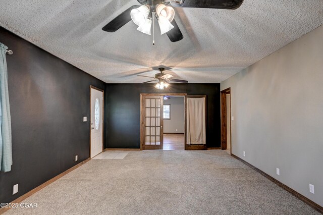 unfurnished room with baseboards, a ceiling fan, light colored carpet, and a textured ceiling