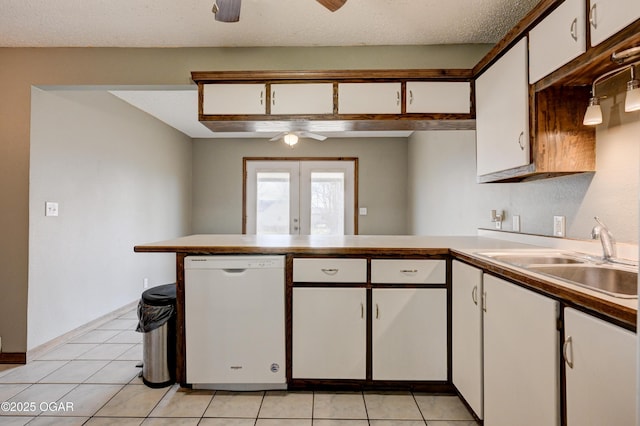 kitchen featuring white cabinets, white dishwasher, a sink, ceiling fan, and a peninsula