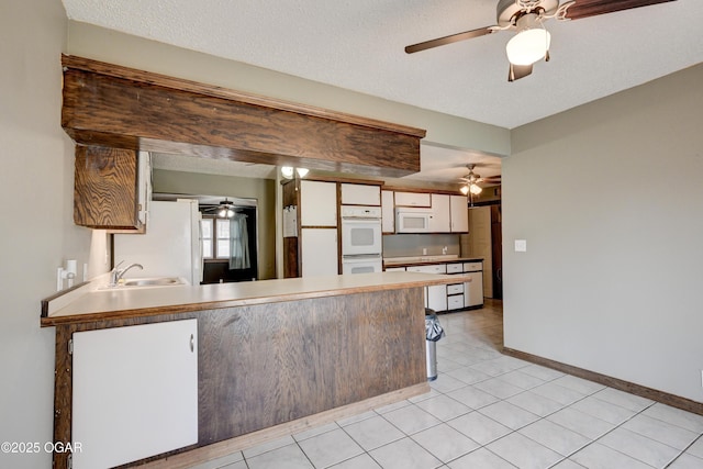 kitchen with a peninsula, ceiling fan, a sink, and white appliances
