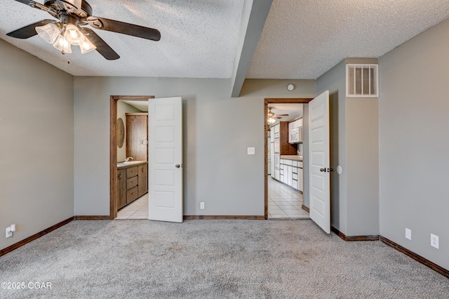 unfurnished bedroom featuring visible vents, light colored carpet, baseboards, and a textured ceiling