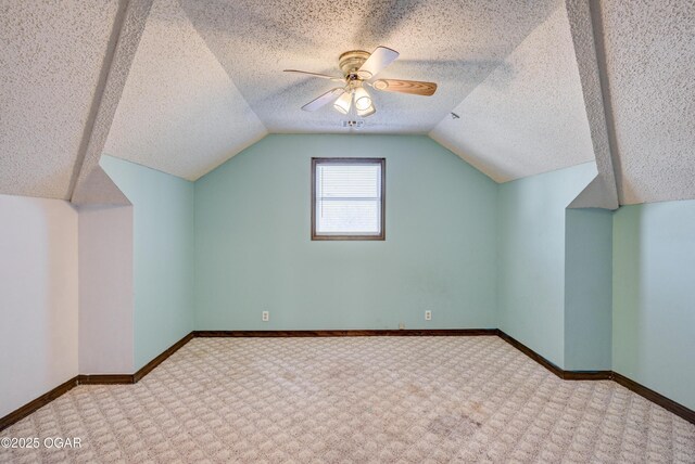 additional living space featuring baseboards, vaulted ceiling, a textured ceiling, and a ceiling fan