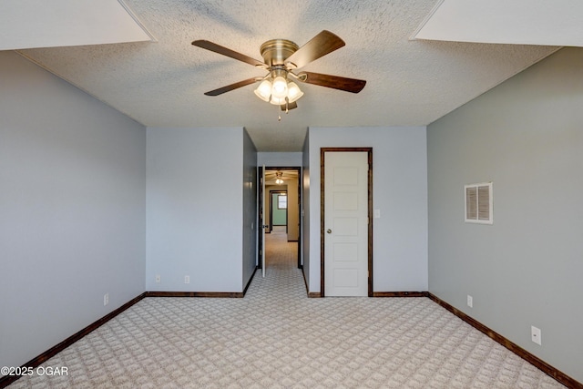 carpeted spare room with visible vents, baseboards, a textured ceiling, and ceiling fan
