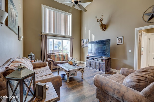 living room featuring baseboards, a high ceiling, a ceiling fan, and wood finished floors