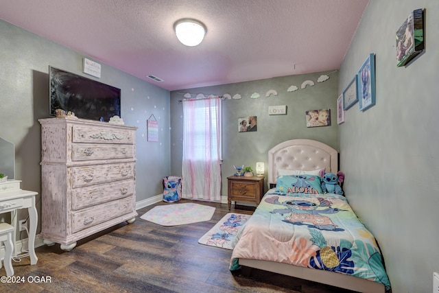 bedroom featuring visible vents, baseboards, wood finished floors, and a textured ceiling