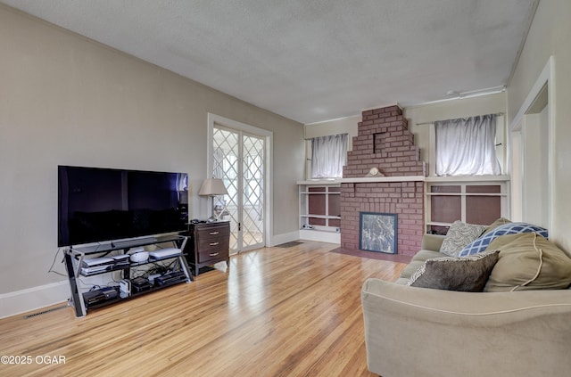426 N Byers Ave, Joplin, MO 64801 - living area with light wood-style floors, baseboards, a textured ceiling, and a brick fireplace