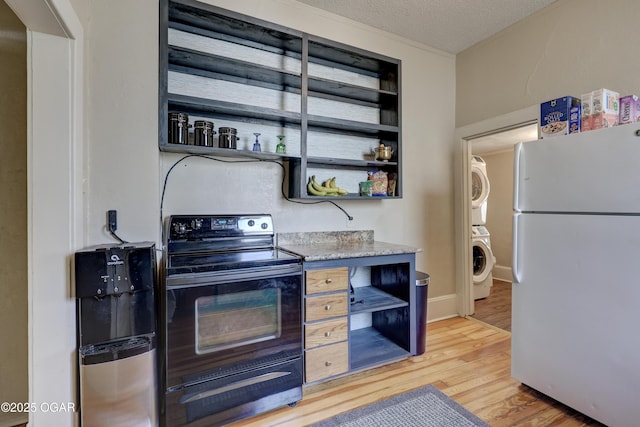 426 N Byers Ave, Joplin, MO 64801 - kitchen featuring stacked washer and dryer, freestanding refrigerator, black electric range, and open shelves