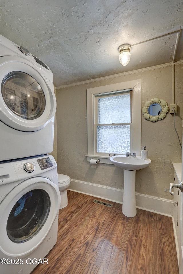 426 N Byers Ave, Joplin, MO 64801 - clothes washing area with ornamental molding, stacked washer and clothes dryer, wood finished floors, and laundry area