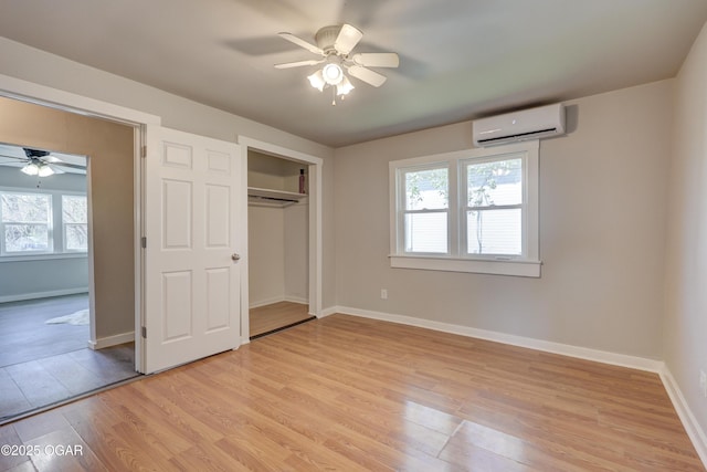unfurnished bedroom featuring light wood finished floors, an AC wall unit, and baseboards