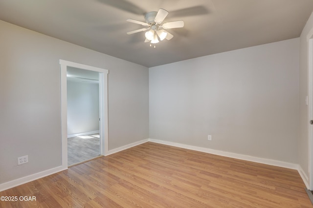 empty room with ceiling fan, light wood-type flooring, and baseboards