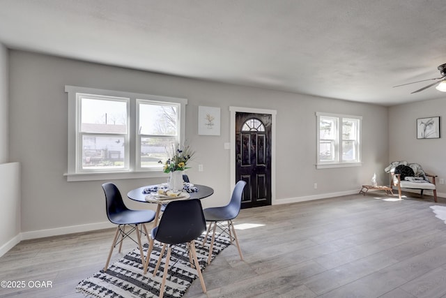 dining space featuring light wood-style floors, baseboards, and ceiling fan