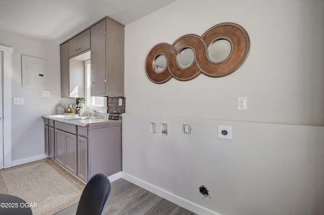 washroom with electric dryer hookup, laundry area, baseboards, and wood finished floors